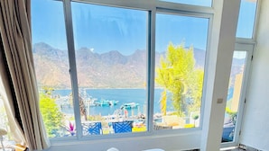 Quarto de hotel com uma cama grande, vista para um lago e montanhas ao fundo.