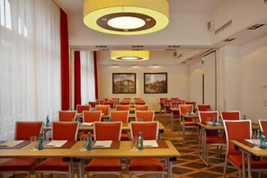 A conference room with rows of tables and chairs, equipped with water bottles and notepads. - H+ Hotel Lübeck (Lubeck)