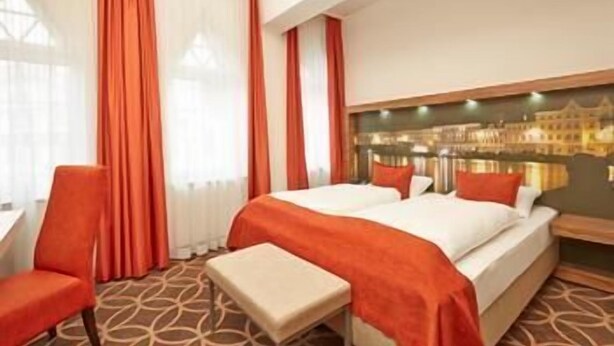 A hotel room with a large bed, a desk, and a chair. - H+ Hotel Lübeck (Lubeck)