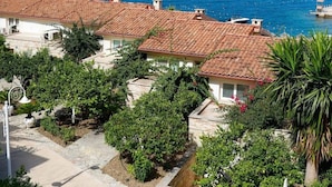 A coastal property with terracotta-roofed buildings, a clear view of the sea, and a well-maintained garden. - Family Seaview Condo Bougainville Bay (Sarande)