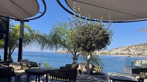 An outdoor seating area with a view of the sea and a hillside town. - Family Seaview Condo Bougainville Bay (Sarande)