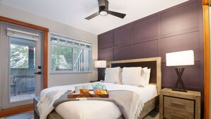 Ein Schlafzimmer mit Bett, Nachttischen, Deckenventilator, Fenster und einem Balkon.