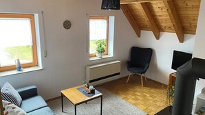 Un salon confortable avec un canapé, une table, un fauteuil, un téléviseur et une cheminée.