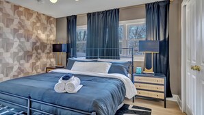 Un dormitorio moderno con cama, dos mesitas de noche, cómoda y ventana con cortinas.