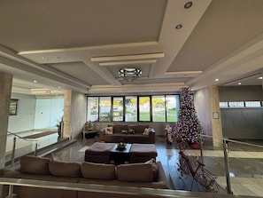 A spacious lobby with a large Christmas tree, comfortable seating, and a staircase leading to other areas. - Tropical family Apt at Marbella del Caribe (Carolina)
