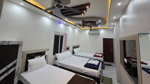 A hotel room with two beds, a ceiling fan, recessed lighting, an air conditioning unit, and a large mirror. - Srikhetra Palace (Puri)