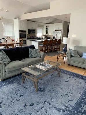 Uma sala de estar com sofá, mesa de centro e um espaço de jantar com cadeiras e mesa.