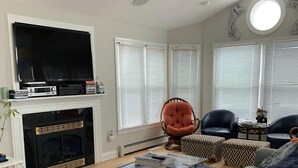 A living room with a fireplace, a television, a sofa, a coffee table, and a chair. - Ship Bottom 5 BR Ocean block -Pool (Ship Bottom)