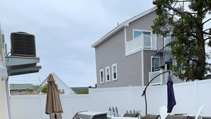 A backyard with a barbecue grill, outdoor furniture, a white fence, and a house in the background. - Ship Bottom 5 BR Ocean block -Pool (Ship Bottom)