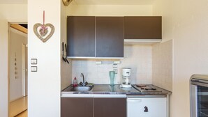 A compact kitchen with a sink, a coffee maker, and a small refrigerator. - Le Cocon du Chaud Costet - Avec balcon (Le Tholy)