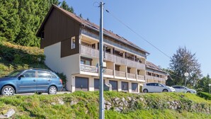 A multi-story building with balconies, parked cars, and a clear sky. - Le Cocon du Chaud Costet - Avec balcon (Le Tholy)