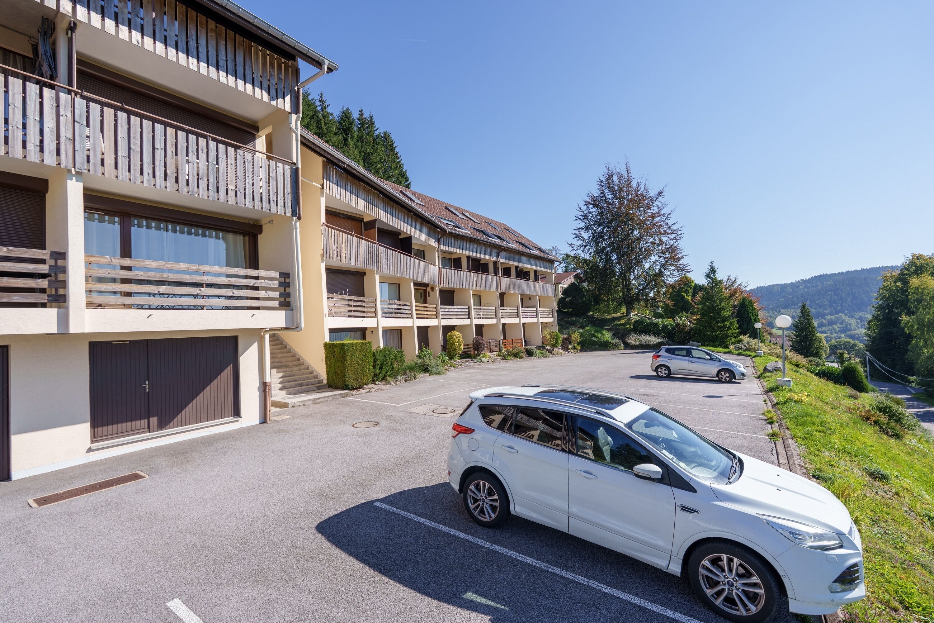 Un hôtel à plusieurs étages, doté de balcons, d’un parking et situé dans un cadre montagneux.