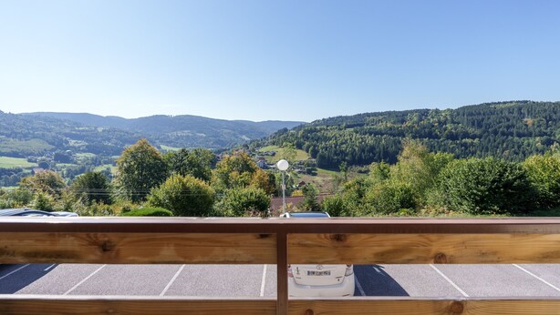 A wooden deck with a view of a parking area and a mountainous landscape. - Le Cocon du Chaud Costet - Avec balcon (Le Tholy)