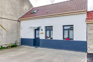 A building with a red-tiled roof, a black door, and windows with flower boxes. - Gîte des Mouettes - Avec terrasse (Ghyvelde)