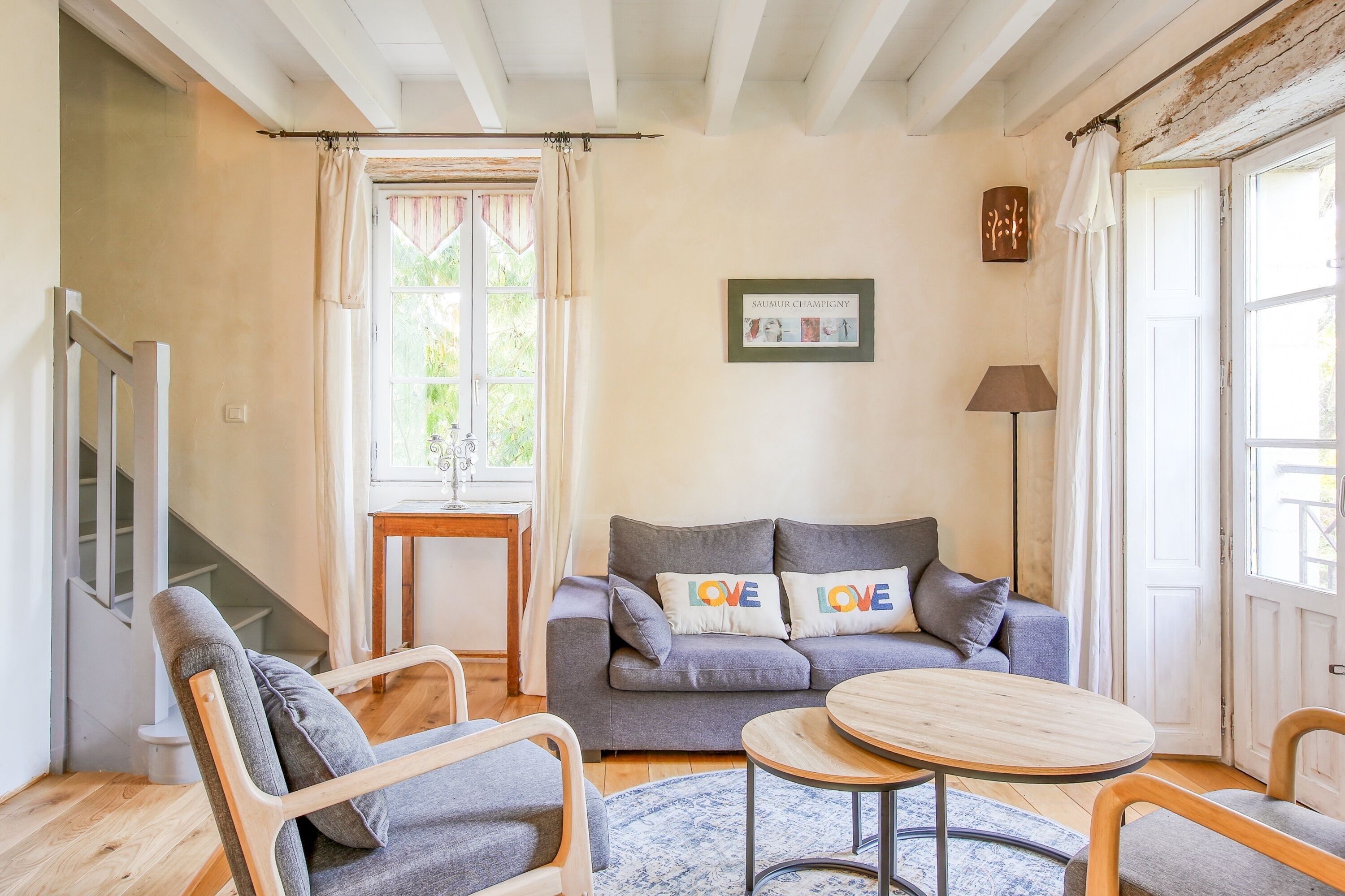 Un salon comprenant un canapé, deux fauteuils, une petite table, une lampe et un tableau encadré accroché au mur.