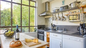 Une cuisine moderne dotée d’une grande fenêtre, d’appareils électroménagers en acier inoxydable et d’une variété d’ustensiles de cuisine et de vaisselle.