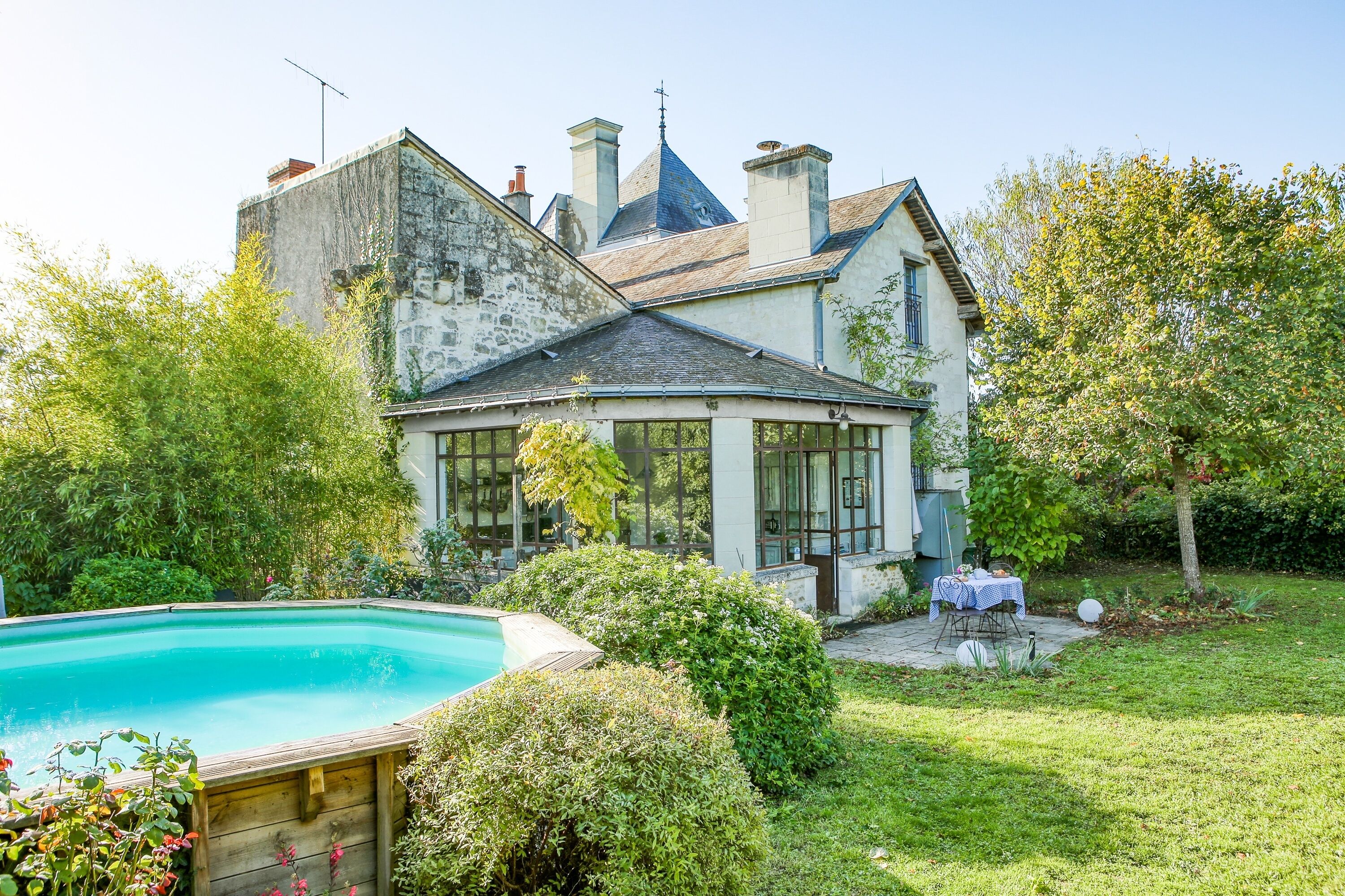 A large house with a swimming pool, surrounded by lush greenery and a well-maintained lawn.