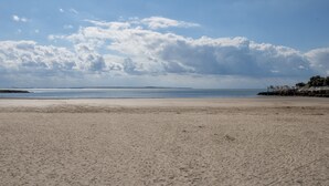 Une plage avec un ciel dégagé et une terre lointaine à l’horizon.