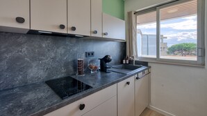 Une cuisine moderne dotée d’un plan de travail noir, de meubles blancs, d’un four encastré et d’une fenêtre donnant sur l’extérieur.