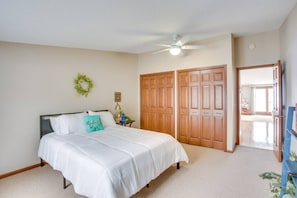 A bedroom with a bed, a nightstand, a ceiling fan, and a wardrobe.