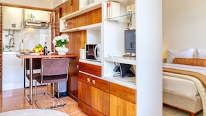 A compact hotel room with a kitchenette, a dining area, and a bed.