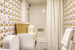 Une salle de bain équipée d’un lave-linge, d’une baignoire et d’une douche.