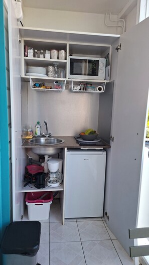 A compact kitchenette with a microwave, sink, and coffee maker.
