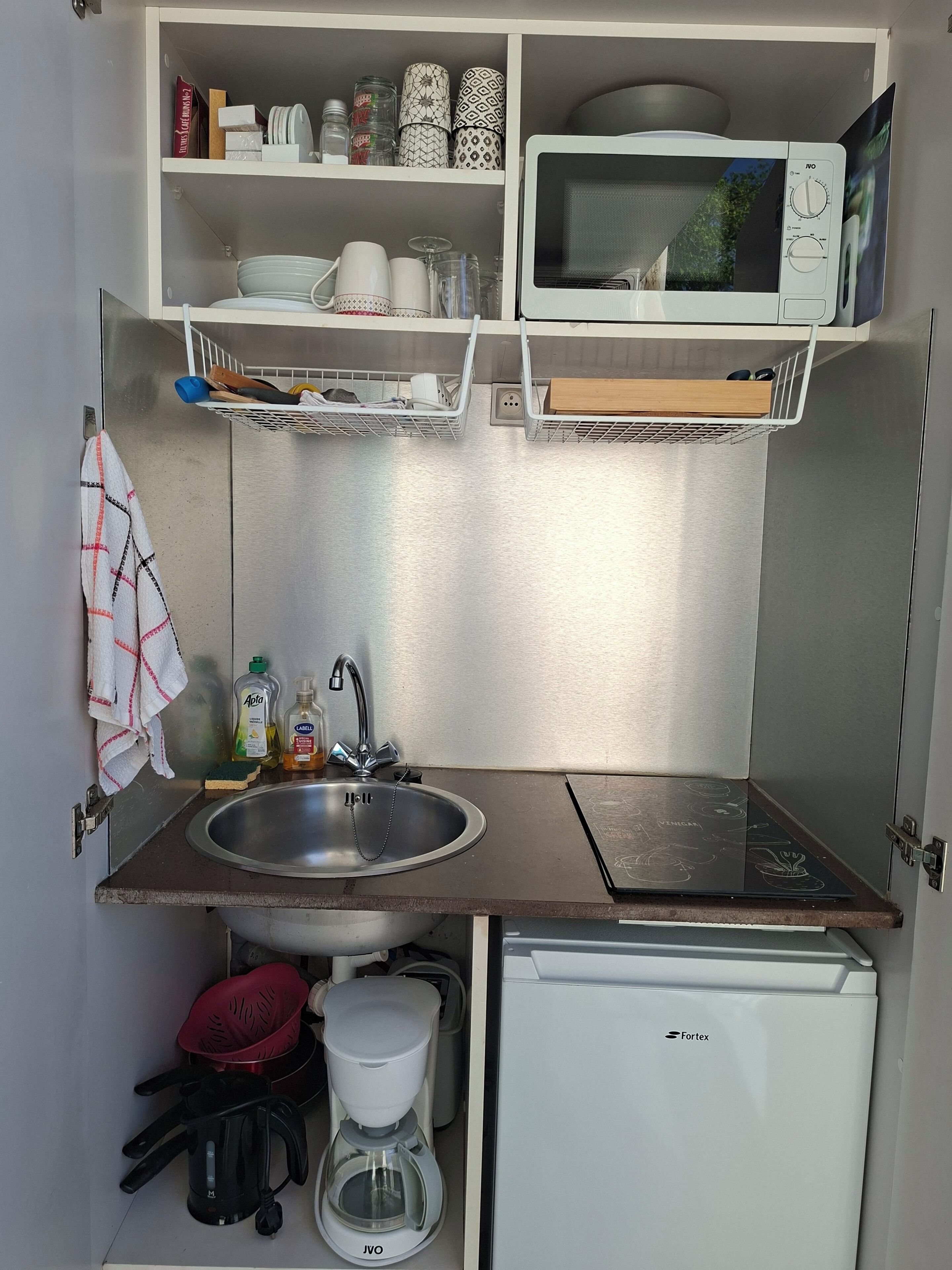 Eine kleine Küchenzeile mit Spüle, Mikrowelle und kleinem Kühlschrank.