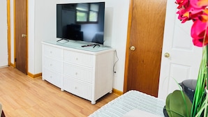A room with a television on a white wicker dresser, wooden doors, and a plant. - Pocono Ridge Inn (East Stroudsburg)