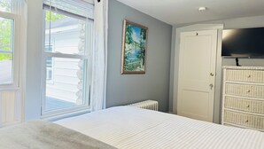 A bedroom with a bed, a radiator, a television, and a door. - Pocono Ridge Inn (East Stroudsburg)