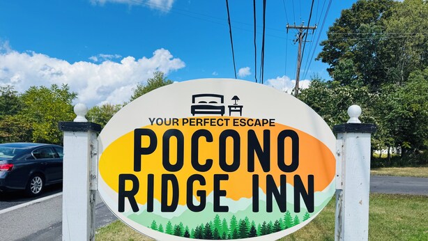 A sign for Pocono Ridge Inn with a mountain and trees illustration. - Pocono Ridge Inn (East Stroudsburg)
