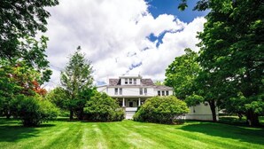 A two-story house with a front porch, surrounded by well-maintained lawns and trees. - Pocono Ridge Inn (East Stroudsburg)
