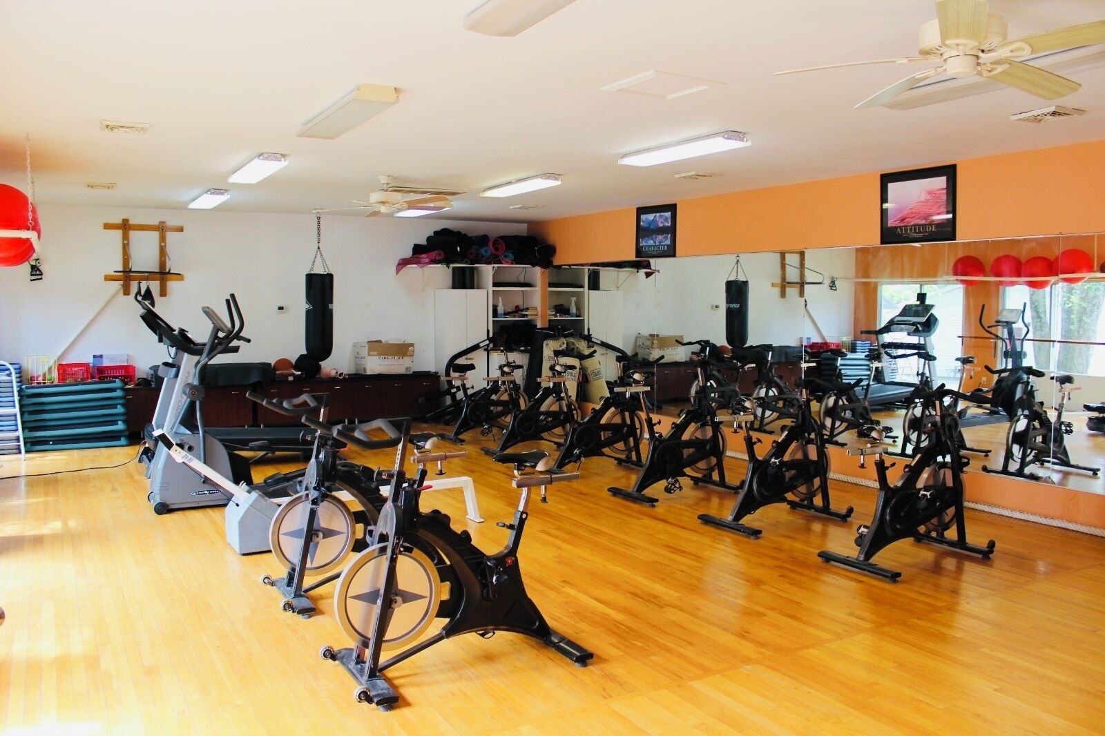 A gym with multiple stationary bikes, a punching bag, and a mirror wall.