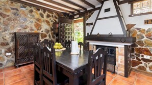 Un coin repas rustique avec un mur en pierre, des poutres en bois et une cheminée.