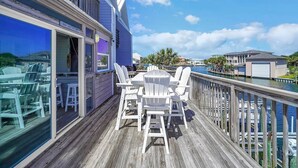 A wooden deck with a table and chairs, overlooking a body of water and a marina. - Gulf Dreamin' - Waterfront, Destin Harbor, Private Dock, 2 Kings, New to VRBO! (Destin)
