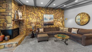 A living room with a stone wall, a sectional sofa, a coffee table, and a fireplace. - Lc305ad2 (Dillon)