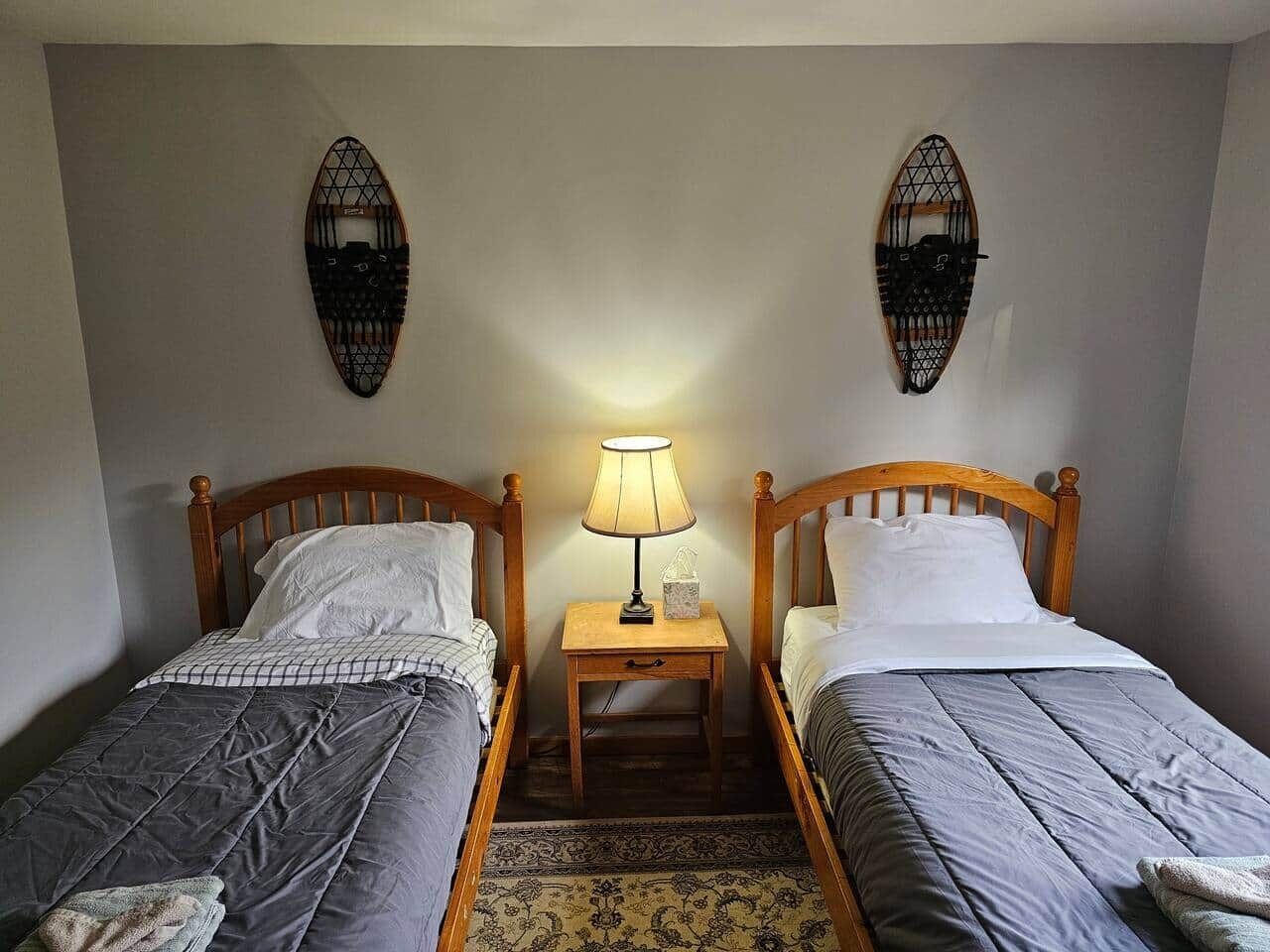 Een kamer met twee enkele bedden, een nachtkastje met een lamp en decoraties aan de muur.