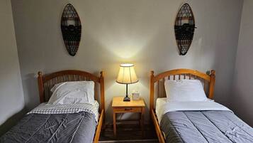 Een kamer met twee enkele bedden, een nachtkastje met een lamp en decoraties aan de muur.