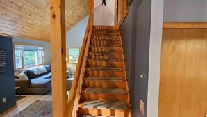 A wooden staircase with a handrail, leading to a room with a gray wall and a wooden door.