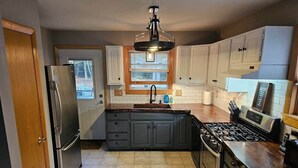 A kitchen with a refrigerator, stove, sink, and cabinets.