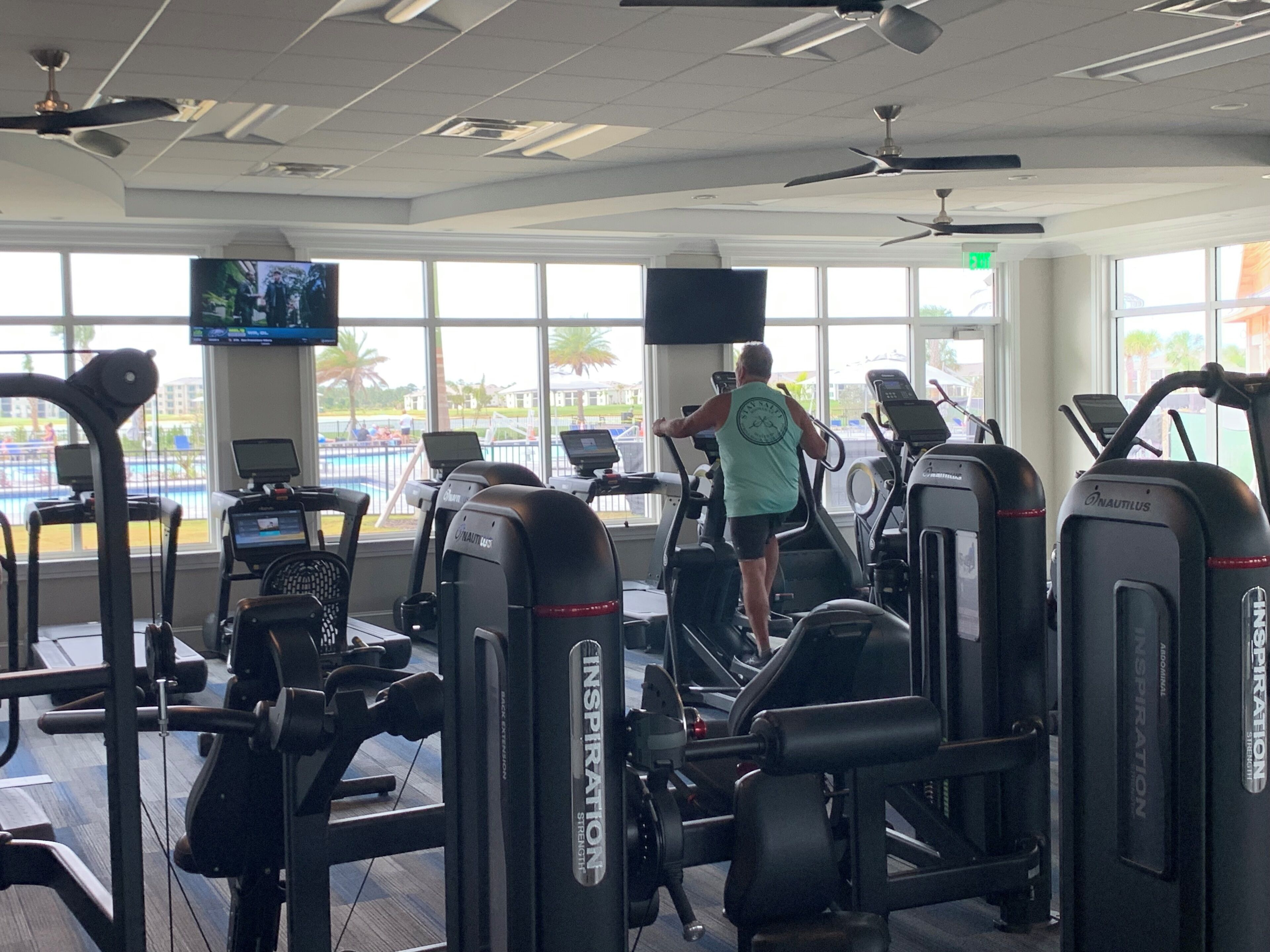 Une salle de sport équipée de tapis de course, d’appareils de musculation et d’un écran de télévision.