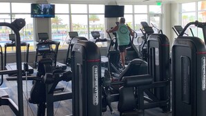 Ein Fitnessstudio mit Laufbändern, Krafttrainingsgeräten und einem Fernseher.