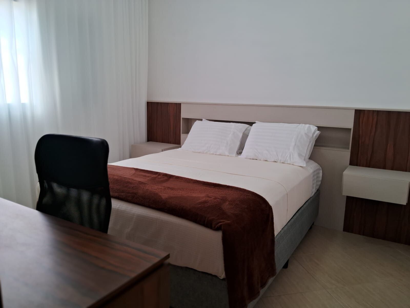 Una habitación de hotel con una cama, un escritorio y una silla.