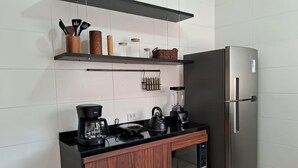 Una cocina moderna con un refrigerador de acero inoxidable, una cafetera, un hervidor y armarios de madera.