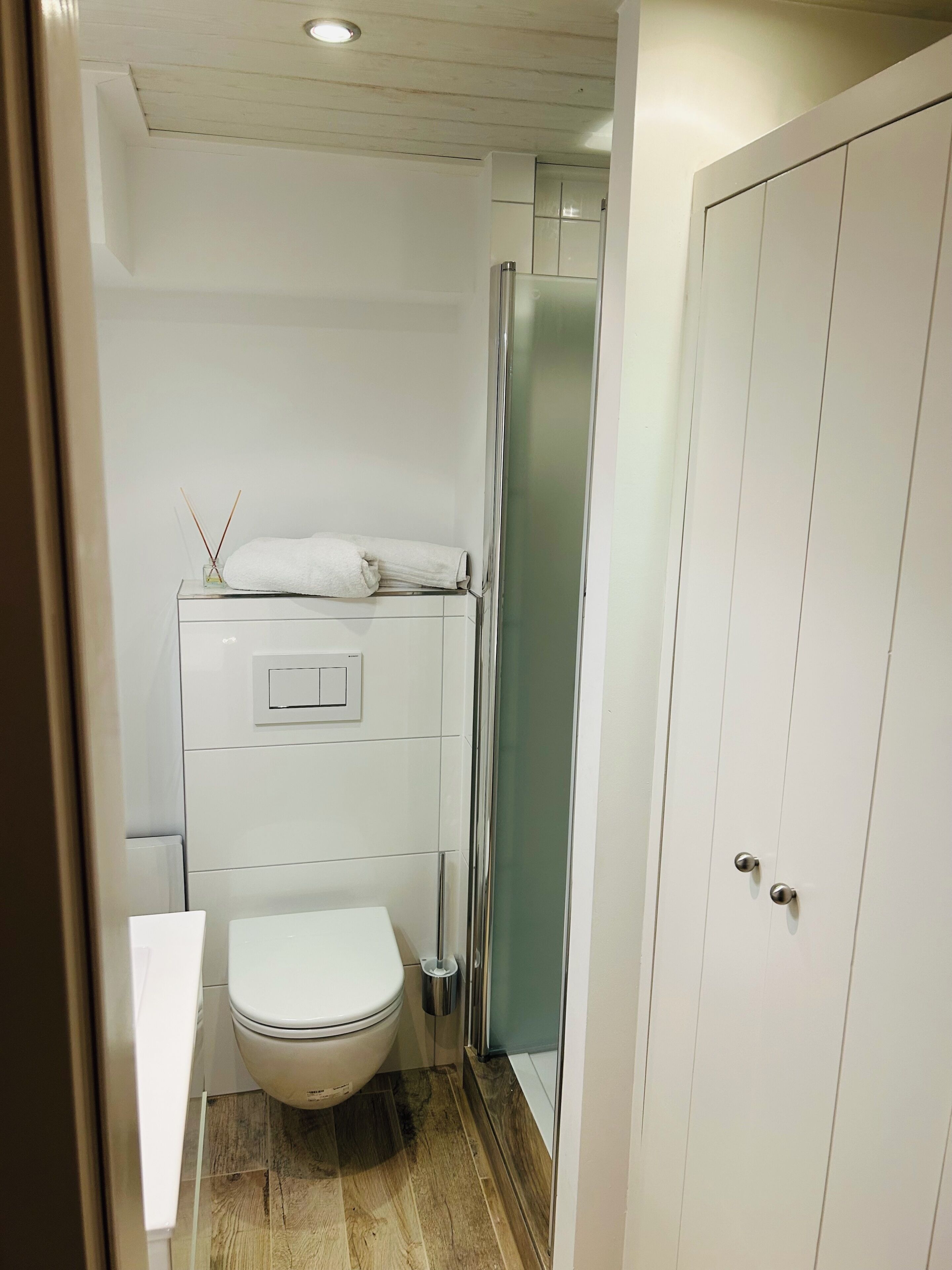 Une petite salle de bain comprenant des toilettes, une douche à parois de verre et un meuble blanc.