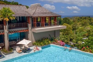 A two-story resort with a swimming pool, outdoor seating, and a view of the ocean. - Avista Hideaway Phuket Patong - MGallery (Phuket)