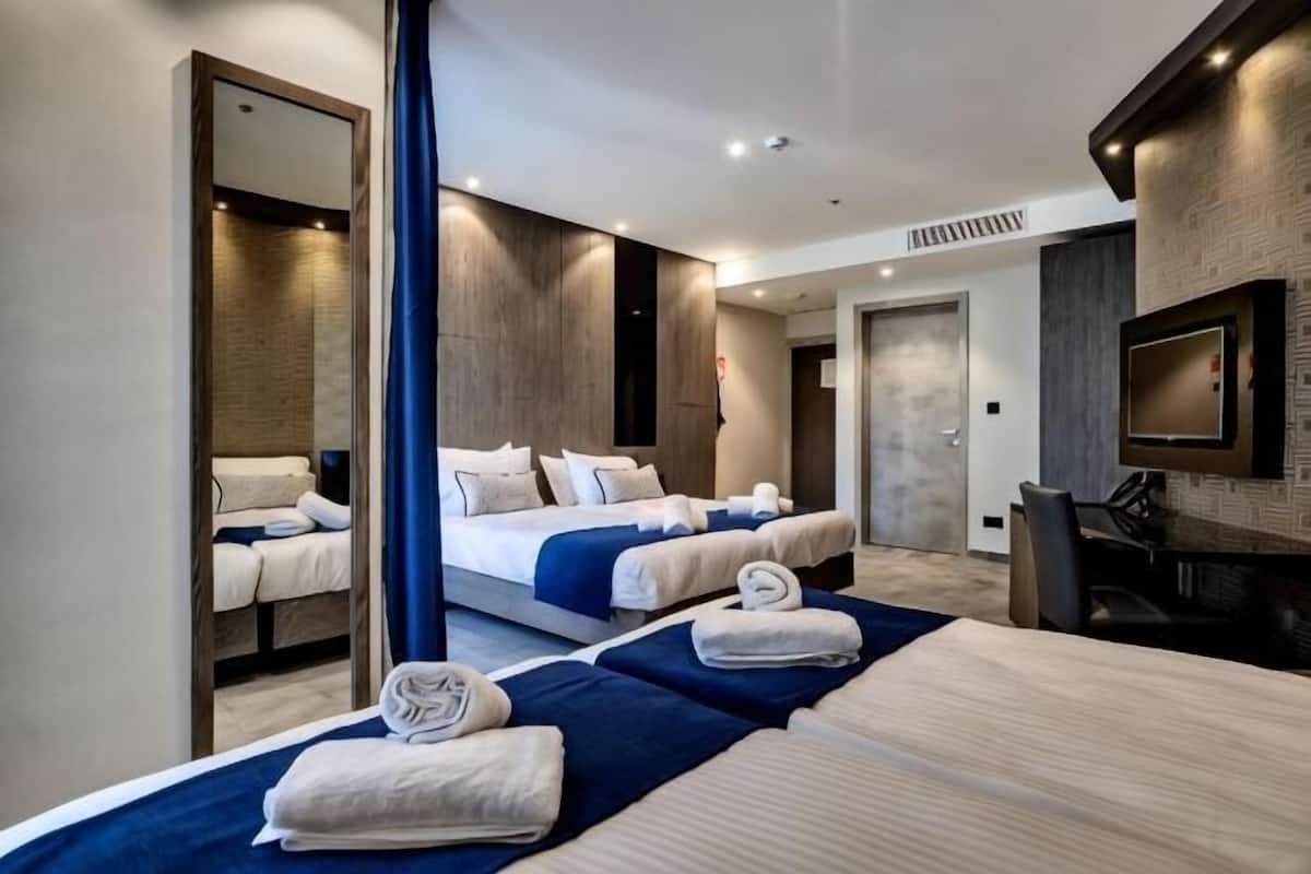 A hotel room with two beds, a TV, a mirror, and a desk.
