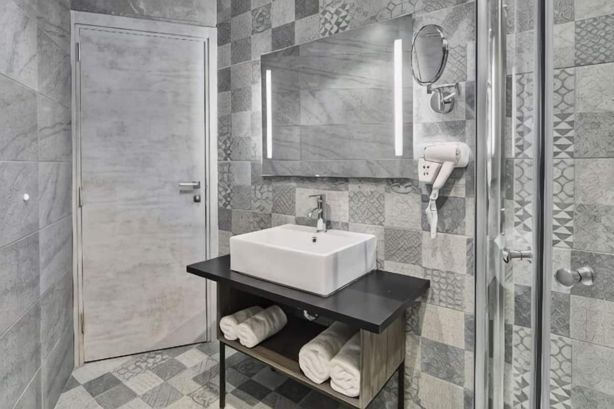 A bathroom with a white sink, a mirror, and a towel rack.