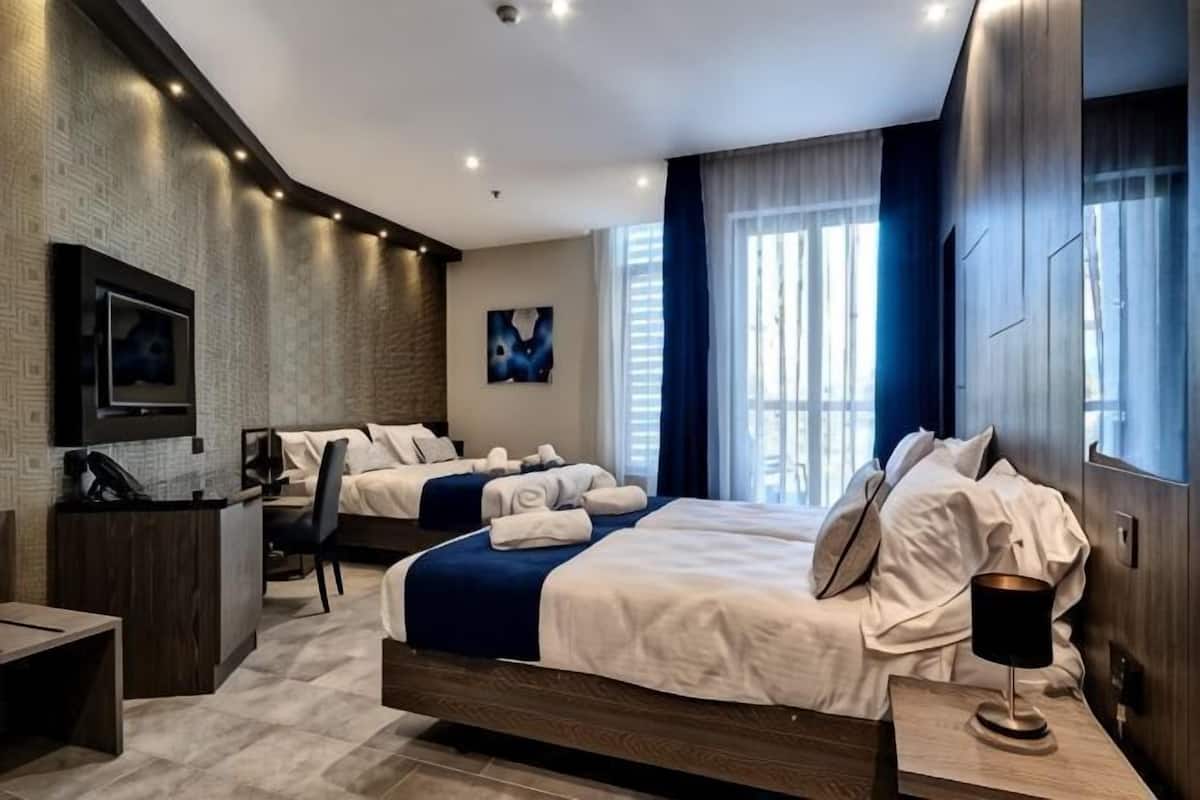 A modern hotel room with a large bed, a desk, and a TV.