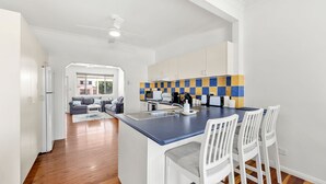 A modern kitchen with a blue countertop, white chairs, and a tiled backsplash. - Barronstown - Pet Friendly with Fire Pit (Callala Beach)